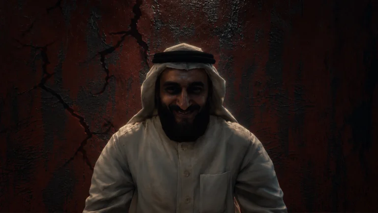 Visuel officiel de Sarab : un homme barbu au sourire inquiétant, coiffé d’un keffieh blanc tenu par un cordon noir et vêtu d’une tunique blanche, se tient face à nous devant un mur sombre rouge et fissuré.